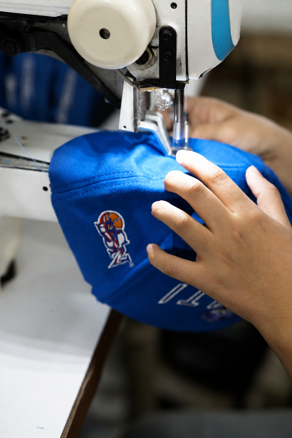 Xtextile operator sewing a blue BSN cap during production